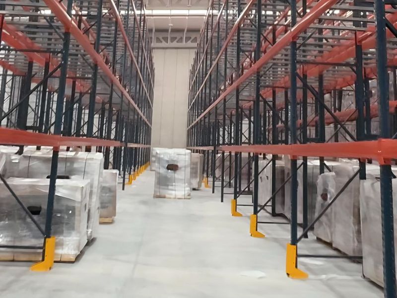 Pasillo entre racks selectivos con protectores de puntal y tarimas emplayadas